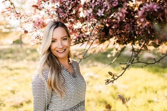 a woman standing in front of a cherry blossom tree