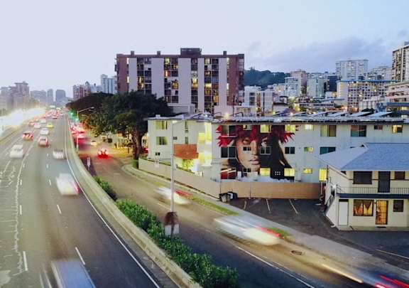 A busy city street with cars and buildings at dusk.