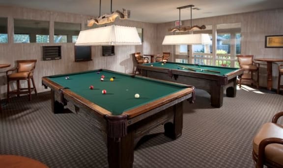 a game room with two pool tables and chairs