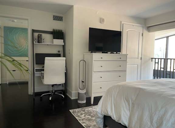 A white bedroom with a bed, dresser, and desk.