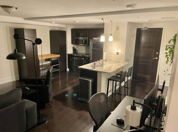 A modern kitchen with dark wood floors and a dining area with a table and chairs.