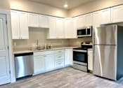 Thumbnail 13 of 27 - A kitchen with white cabinets and stainless steel appliances.