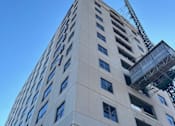Thumbnail 14 of 18 - A tall building with a crane on the top and windows on the side.