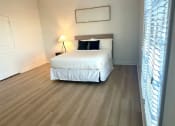 Thumbnail 8 of 13 - a bedroom with a bed and a wooden floor