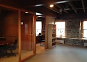 Thumbnail 5 of 8 - A room with a stone wall and a desk with a chair.
