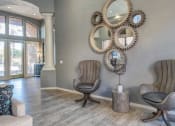 Thumbnail 6 of 24 - Ingleside Apartments Clubhouse sitting area with brown leather chairs, mirrors and light brown hardwood floors