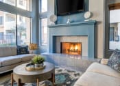 Thumbnail 5 of 24 - Ingleside Apartments Clubhouse Sitting area with blue fireplace with tv above and beige couches