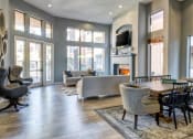 Thumbnail 9 of 24 - Ingleside Apartments Clubhouse with two couches, a dining table, and brown side chairs. Large windows look out to the pool