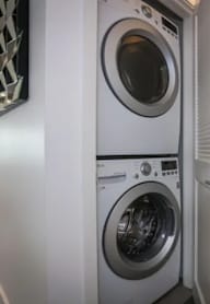 A white washing machine is in a narrow hallway.