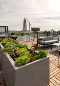 A rooftop patio with a table and chairs and a view of the city.