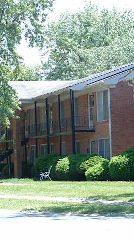 a red brick building with a lawn and trees