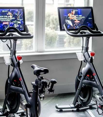 Two stationary bikes in a room with screens on the backrests.