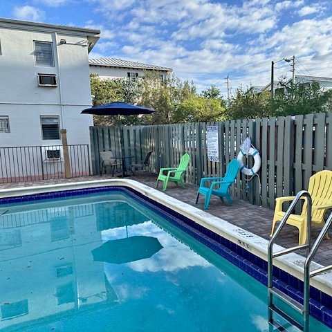 A pool with a blue tiled edge and a white fence in the background.