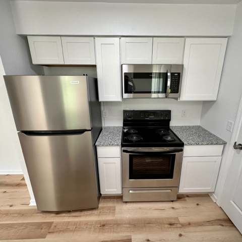 a kitchen with a stove a refrigerator and a microwave