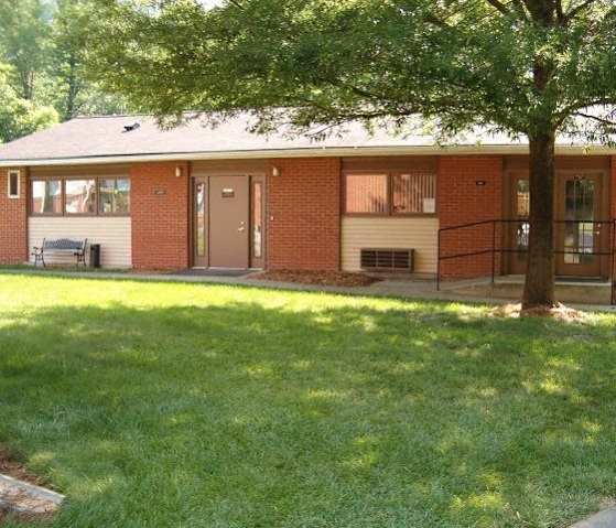 a small brick house with a tree in the yard