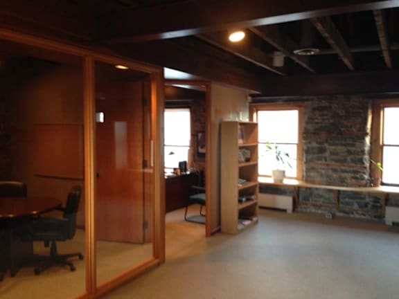 A room with a stone wall and a desk with a chair.