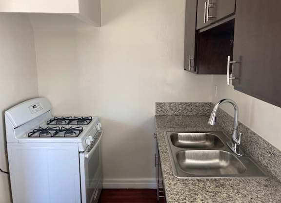 Kitchen with hardwood floors, dark wood cabinets, and gas range at The Western at Rosewood apartments in Los Angeles, California.