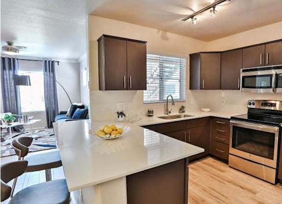 The Highland Apartments kitchen with brown cabinets, stainless appliances and quartz counters