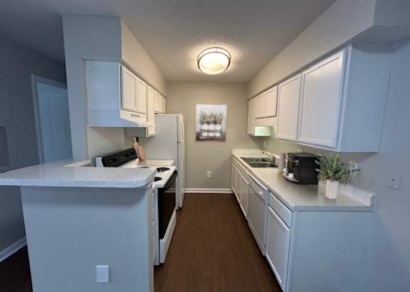 A kitchen with white cabinets and appliances.