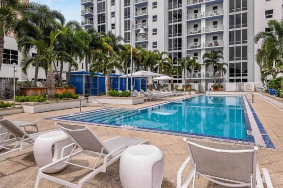 A pool surrounded by chairs and umbrellas in front of a building at Paramount on Lake Eola Apartments, Orlando, Florida