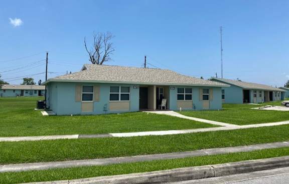 A blue house with a white roof and a white fence in front of it.