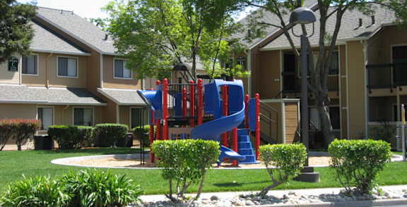 A playground with a blue slide is in front of a building.