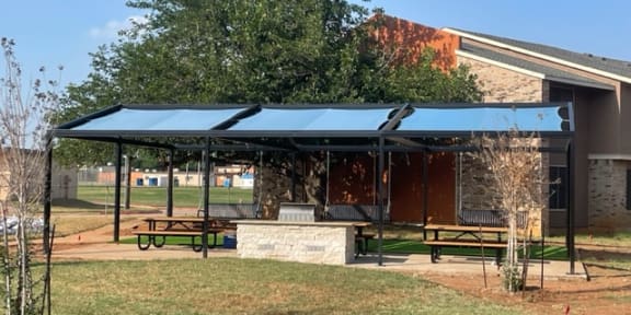 a blue canopy over a picnic area in front of a building