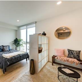 A bedroom with a bed, a bench, and a mirror on the wall.at Prizma, Los Angeles, CA