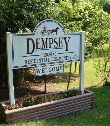 a sign for thedempsey housing residential community in front of a garden