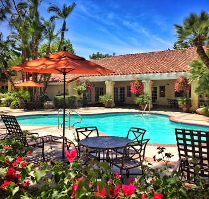 a swimming pool in front of a house with a pool table and umbrella