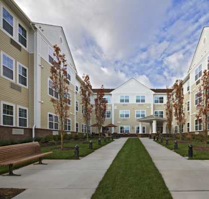 a walkway lined with benches in front of an apartment complex