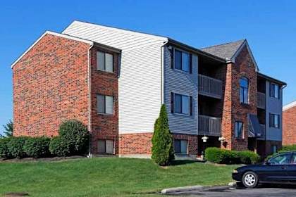 A black car is parked in front of a brick building.