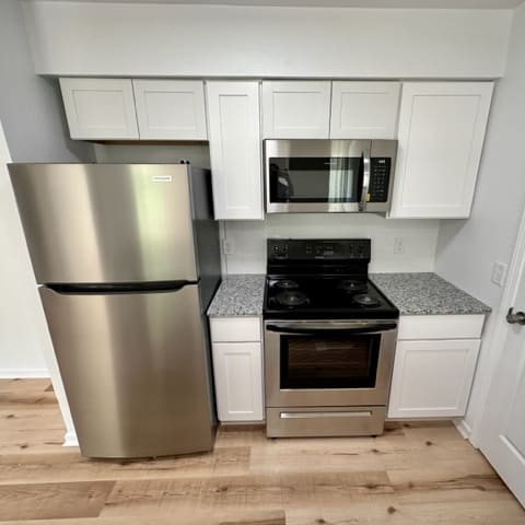 A kitchen with a stainless steel refrigerator and a stove top oven.at Mammoth at the Orchard Apartments, Rogers