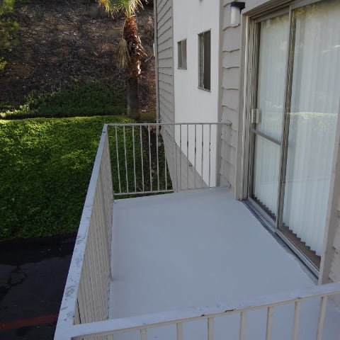 a balcony with a white floor and a sliding glass door