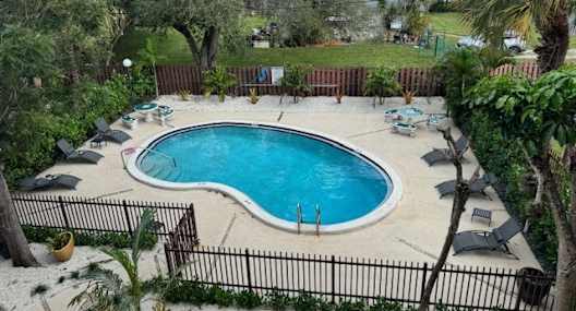 an aerial view of a swimming pool and patio with umbrellas