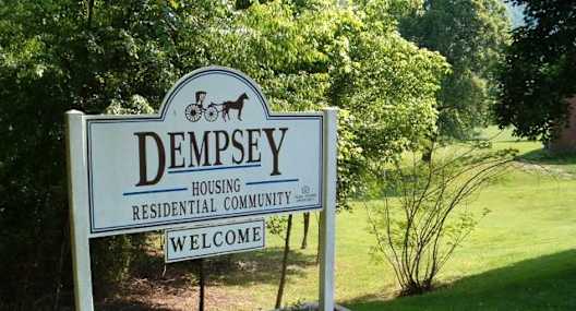 a sign for thedempsey housing residential community in a park