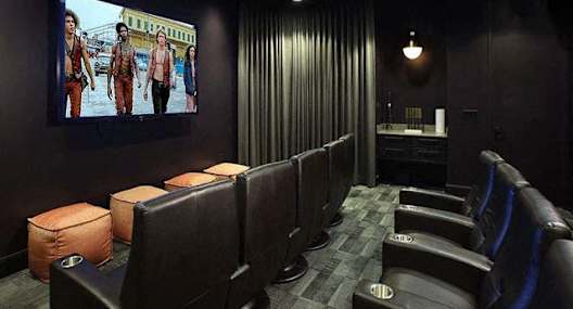 A row of black chairs are lined up in front of a large screen.