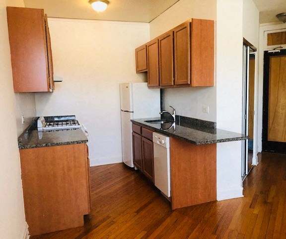 A kitchen with wooden cabinets and a black countertop.