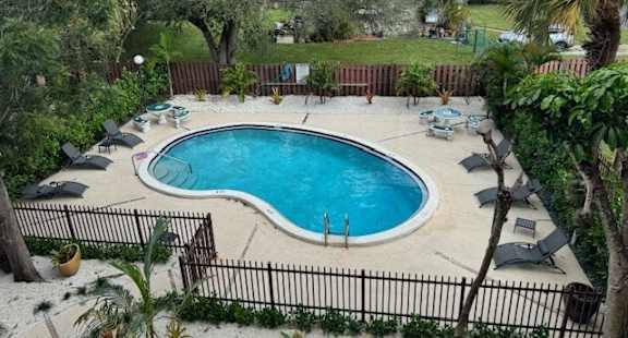 an aerial view of a swimming pool and patio with umbrellas
