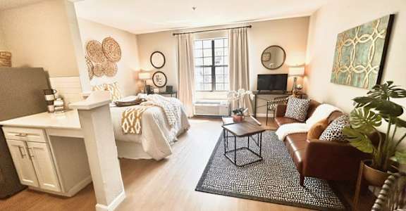 A well-lit bedroom with two beds and a desk.