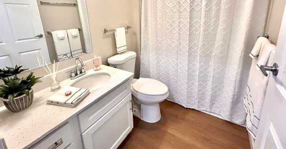 A white bathroom with a toilet, sink, and shower curtain.