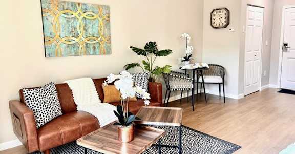 A living room with a brown leather couch, a wooden coffee table, and a painting on the wall.
