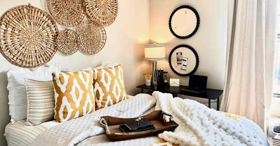 A bedroom with a white bed and a white nightstand with a lamp.