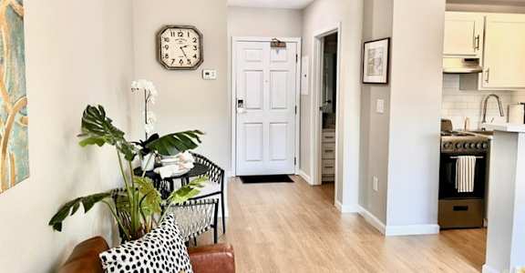 A living room with a brown couch and a clock on the wall.