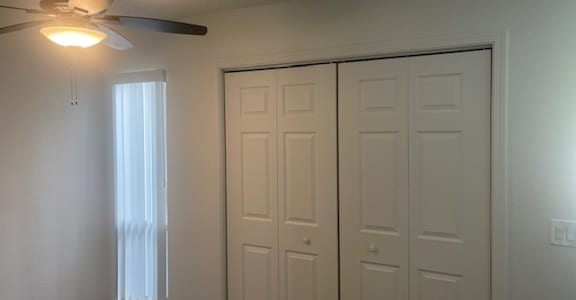 A room with a ceiling fan and three doors.
