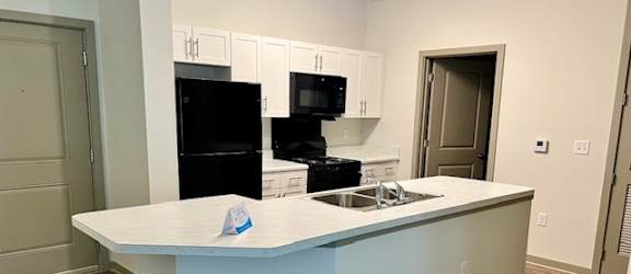 A kitchen with a white counter and a black fridge.at Arbours at Moores Mill, Huntsville