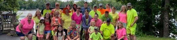 a group of people posing for a picture by a lake
