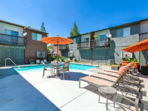 Apartments for Rent Ontario - Encore - Pool Area with Lounge Chairs, Side Tables, and Orange Umbrellas