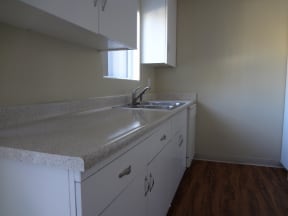 Kitchen with hardwood flooring, window, and spacious cabinets at Villa Knolls Apartments in La Mesa, California.
