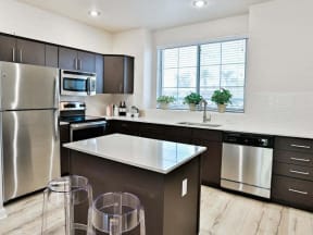 The Highland Kitchen with stainless appliances, dark cabinets, white quartz counters and light faux wood flooring